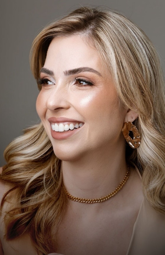 Retrato de paciente sorrindo, com pele iluminada e cabelos loiros ondulados